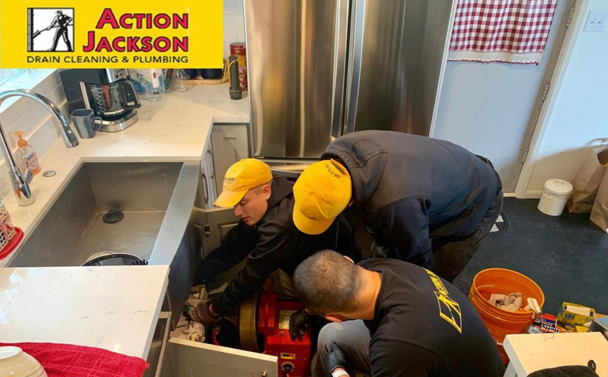 plumbers working on pipes under sink